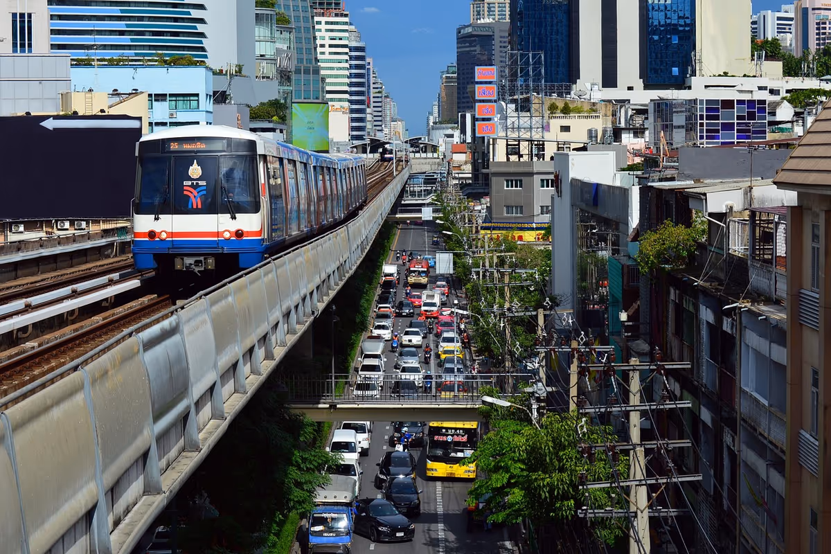 BTS Skytrain train on elevated track above busy street in downtown Bangkok