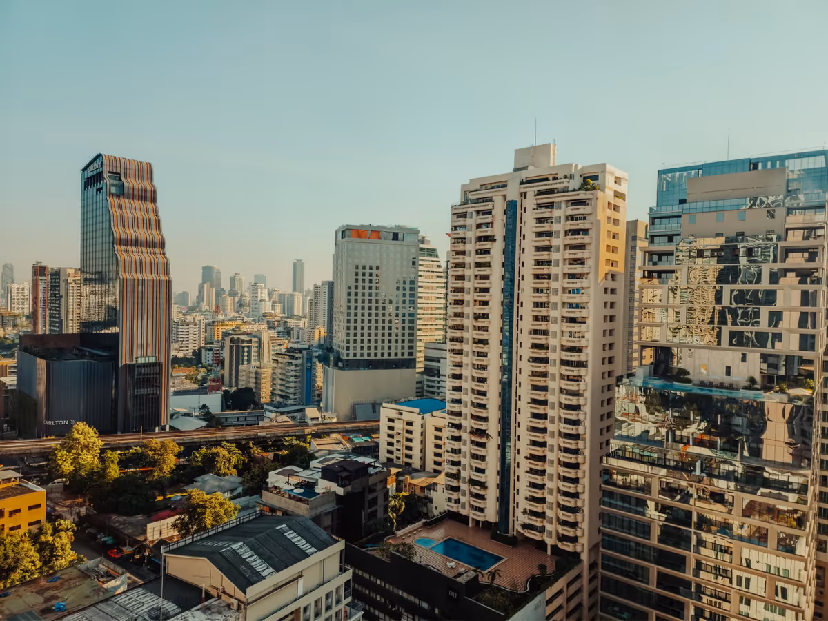 Aerial view of Bangkok condominium towers and skyline at golden hour under clear sky