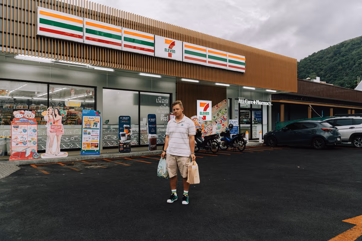 Магазин 7-Eleven в Таиланде, мужчина с пакетами стоит перед входом