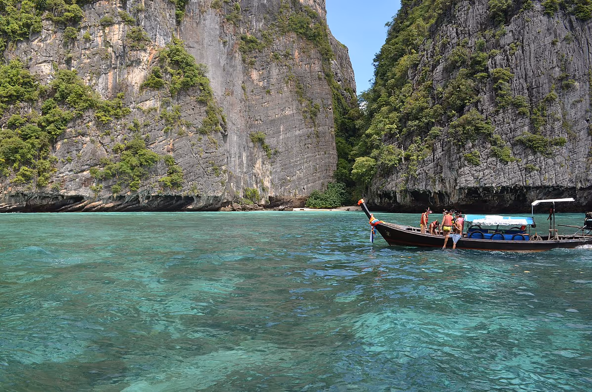 Limestone cliffs and turquoise bay with a longtail boat at Phi Phi Islands, Thailand