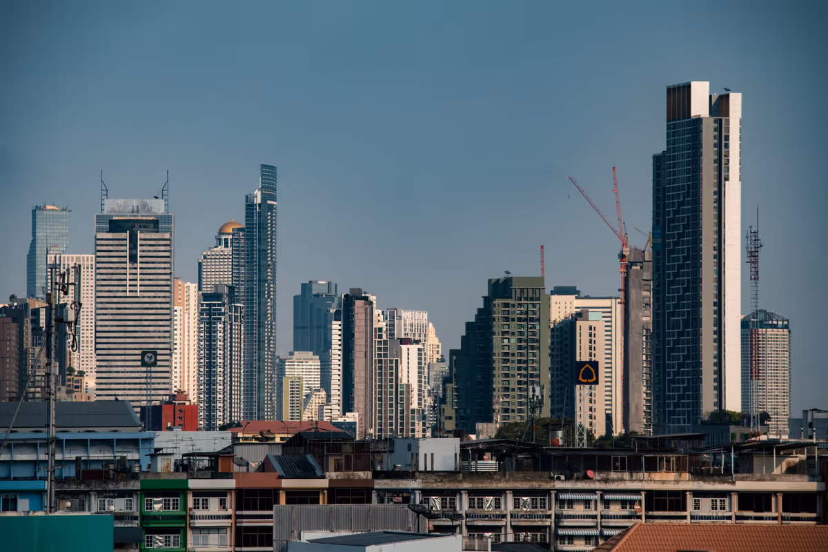 Skyline of Bangkok office towers and construction cranes rising above low-rise buildings