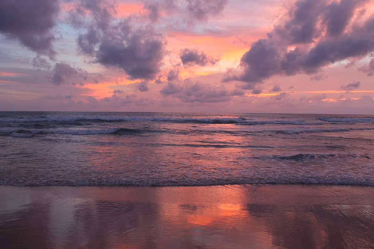 Pink sunset over the sea and waves at Karon Beach on Phuket island