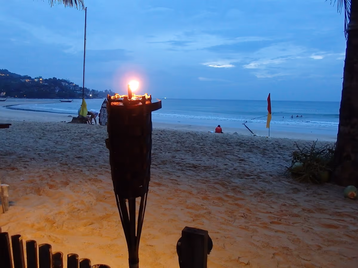Kamala Beach on Phuket at dusk with a lit torch in the foreground