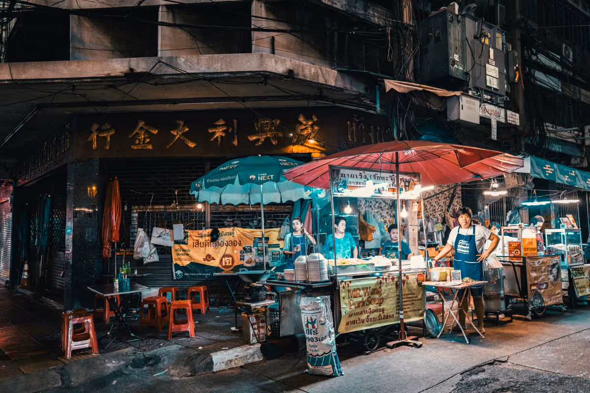 Stands de cuisine de rue nocturnes avec vendeurs sous parasols en Thaïlande