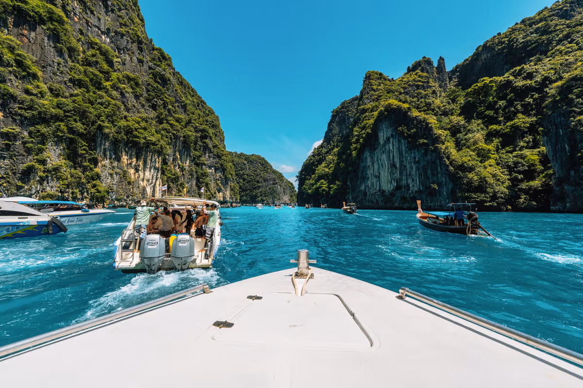 Vue depuis la proue d'un bateau rapide sur une baie étroite aux falaises calcaires et eau turquoise en Thaïlande