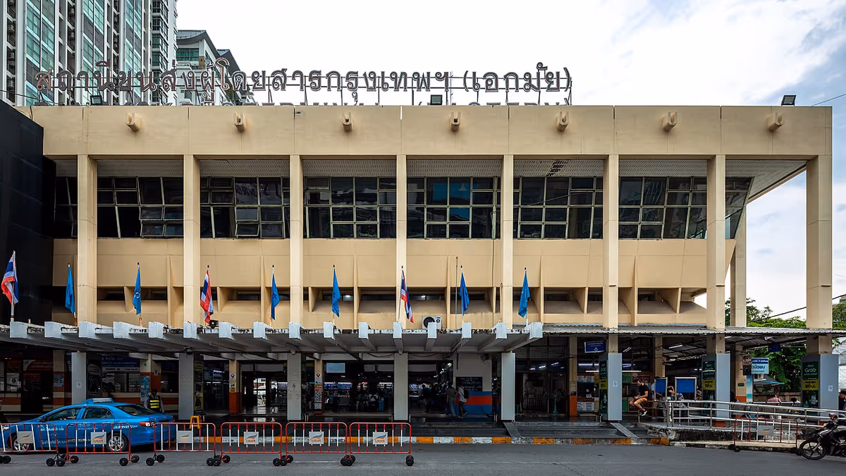 Facade of Ekkamai Eastern Bus Terminal in Bangkok with Thai signage and flags