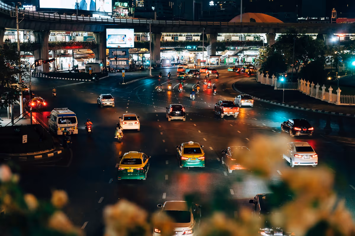 Night traffic with yellow taxis at a busy junction under an elevated road in Bangkok