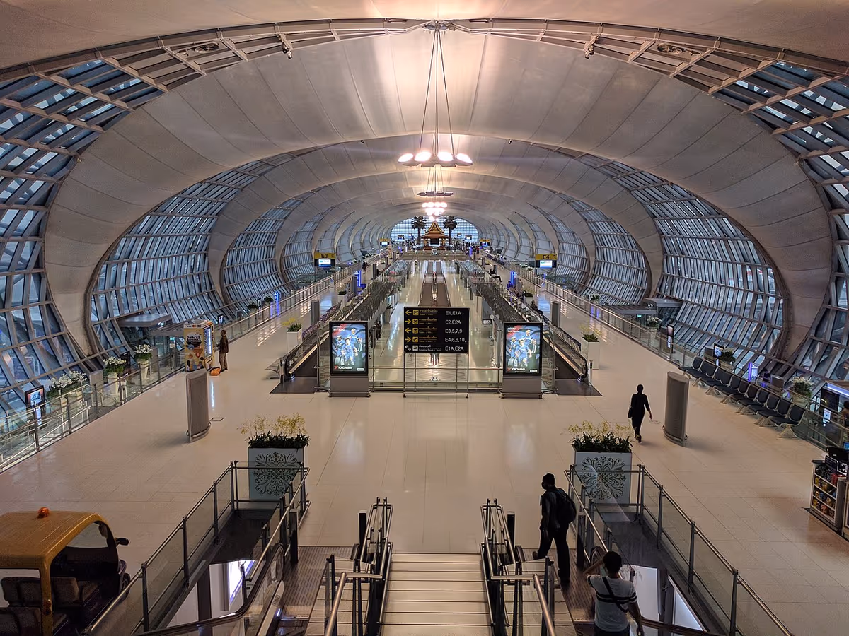 Interior of Suvarnabhumi Airport terminal in Bangkok with curved roof and escalators