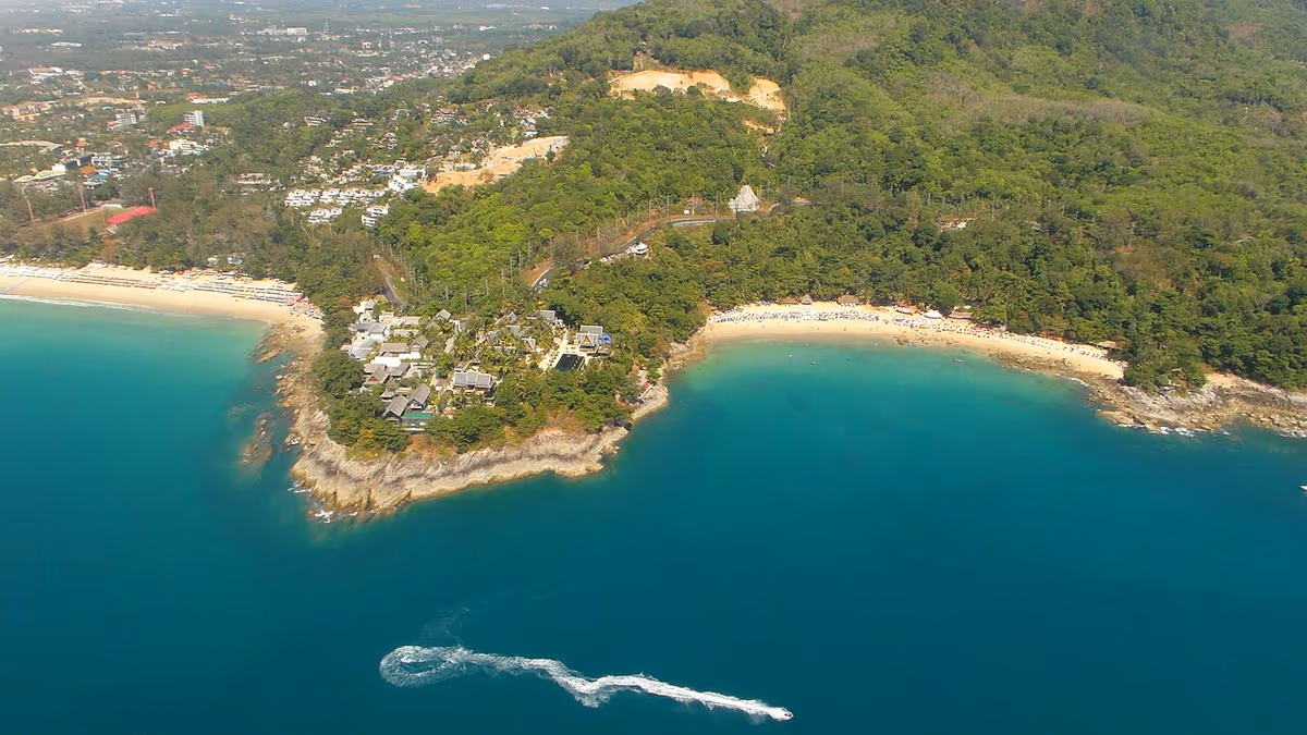 Aerial view of Kamala Beach on Phuket with turquoise sea and a speedboat